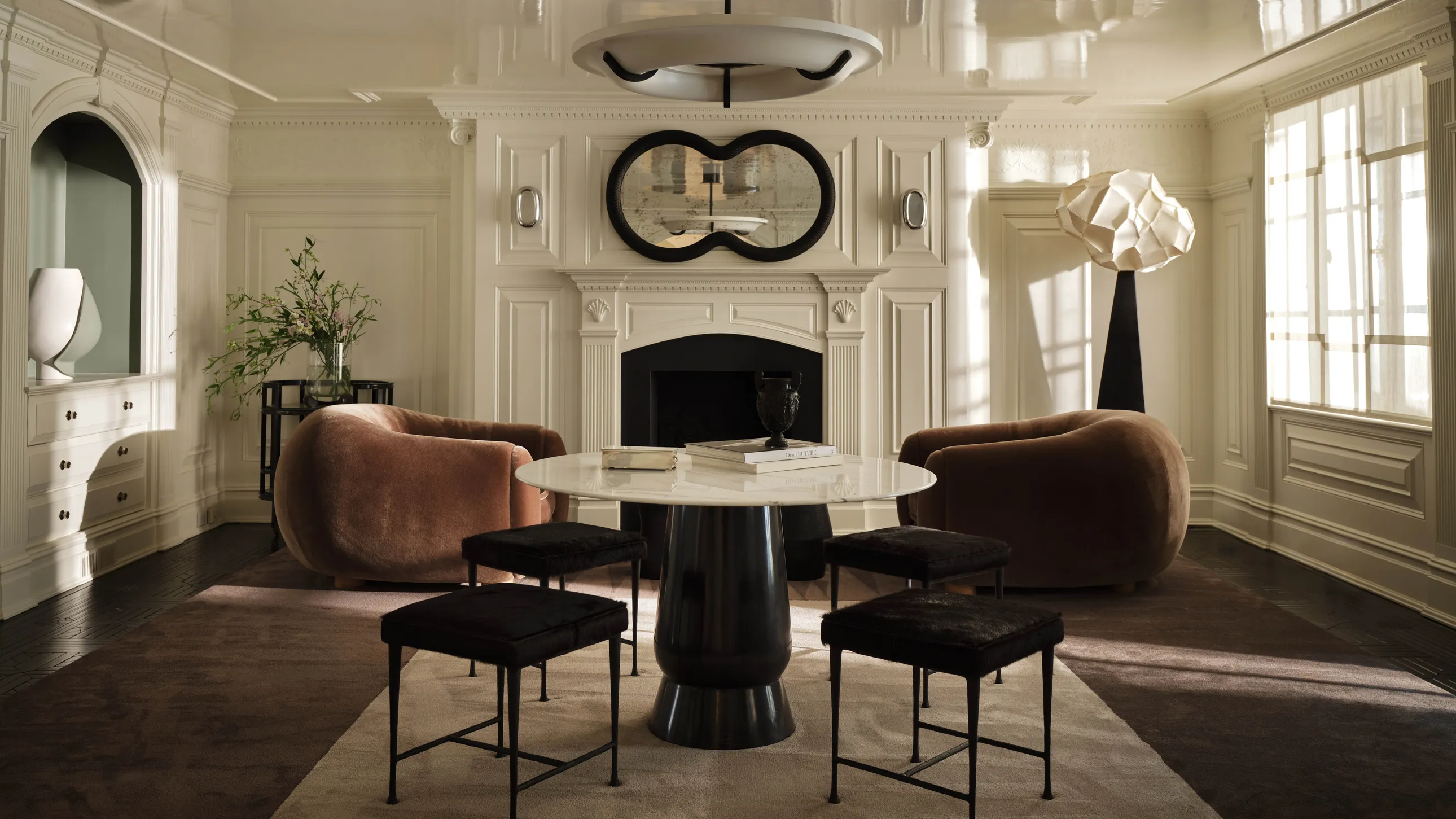 Luxury Interior Design Room With Cream Molding Walls And With Large Windows And With An Antique Fireplace And With Two Brown Velvet Armchairs And With A Round Black Table And With A Cream Rug