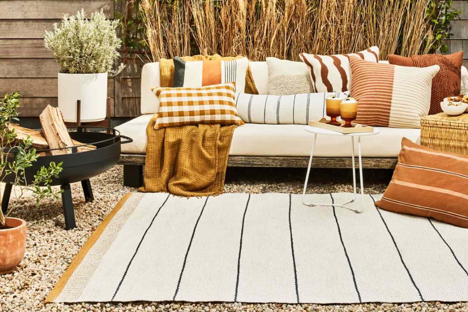 Outdoor Space With Sofas And Plants, And A Main White Rug With Black Stripes